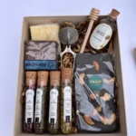 Box de regalo con té en hebras en tubo de vidrio, miel pura, chocolate artesanal con frutos secos y pastelería gourmet.
