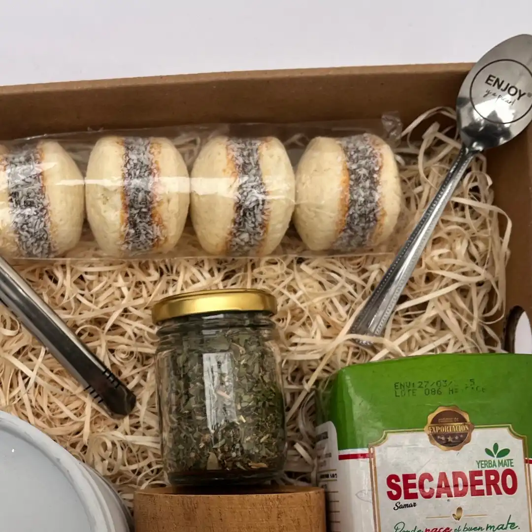 Vista superior de box de regalo con yerba mate, cuchara grabada de Enjoy y alfajores artesanales.